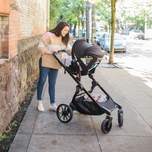 Mom pushing her baby in a Clek Liing infant car seat on a Baby Jogger City Select Stroller