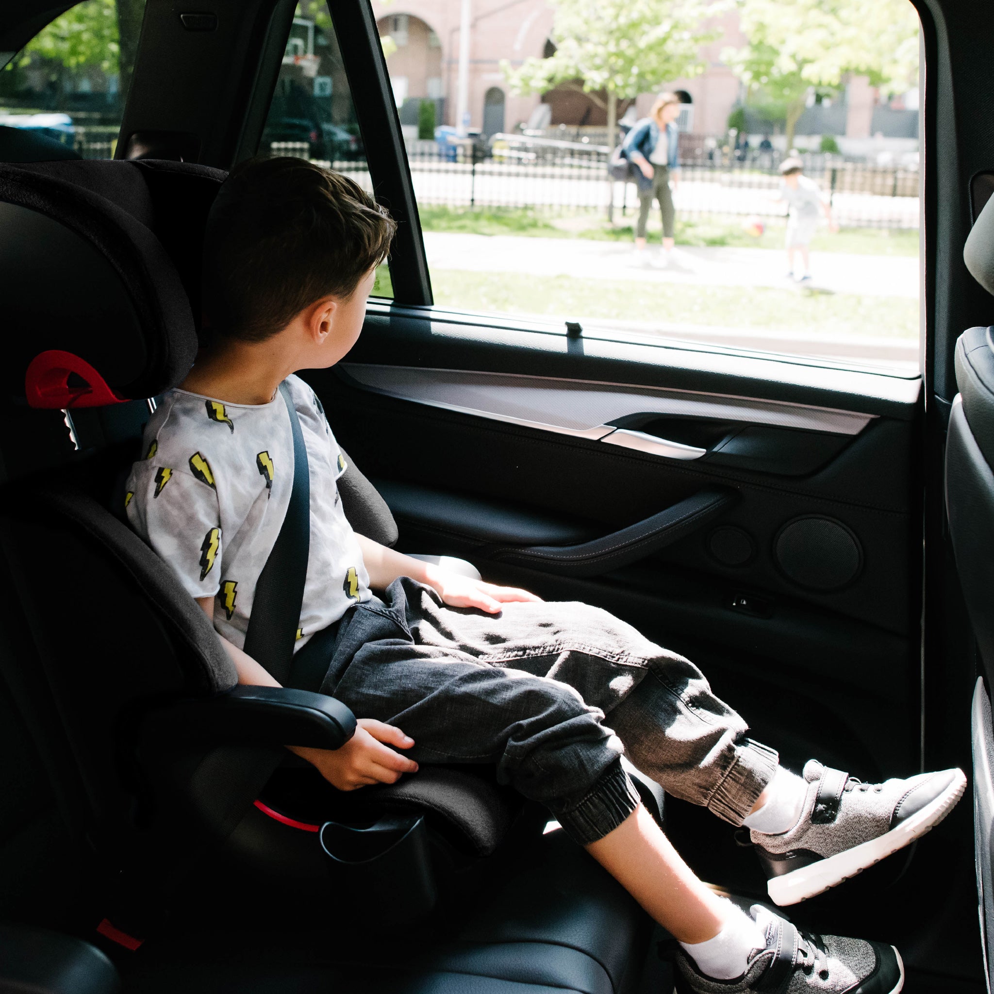 Child sitting in a car seat inside a vehicle with a view of an outdoor scene through the window. all-groups