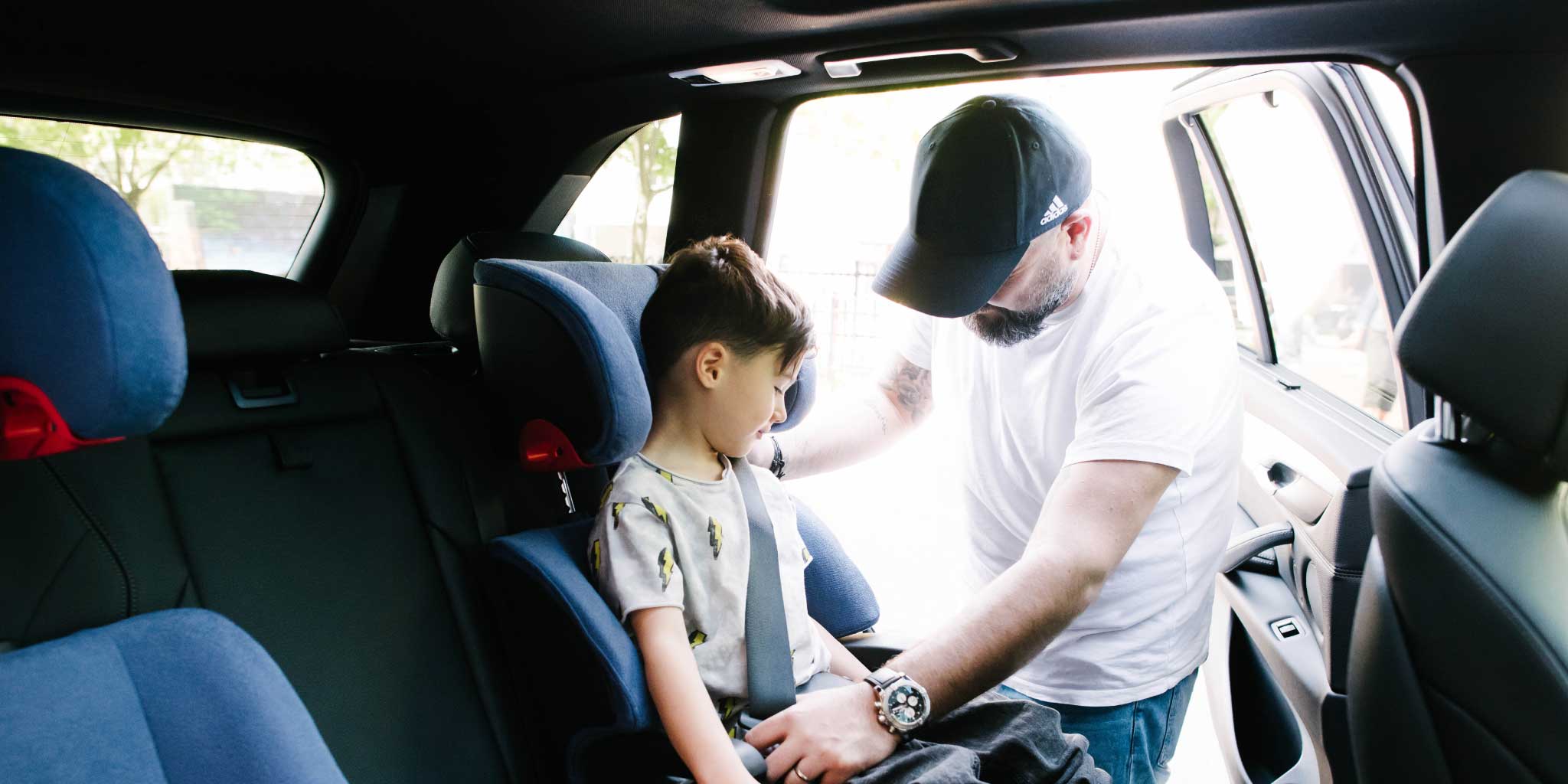 Child being buckled into his Clek Oobr High Back Booster Car Seat