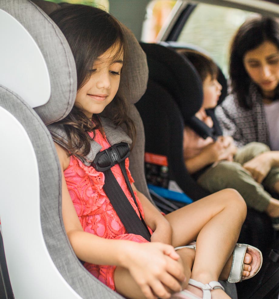 Mom buckling in her son and daughter into their Clek convertible car seats
