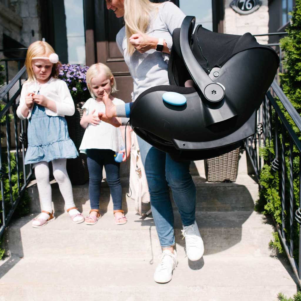 Woman carrying her newborn in a Clek Liing Infant car Seat