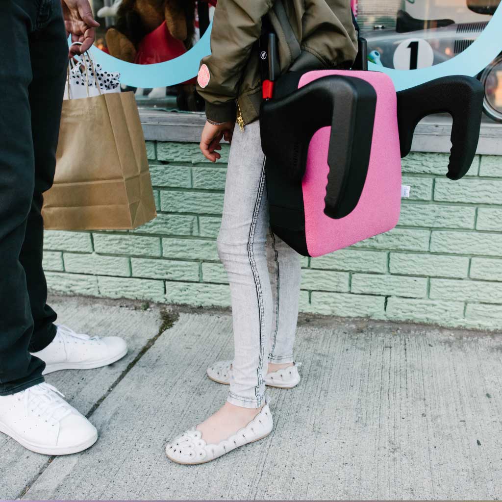 Father and daughter walking while carrying a Clek Olli booster seat 