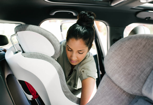 Mom installing a Clek Foonf convertible car seat into her car