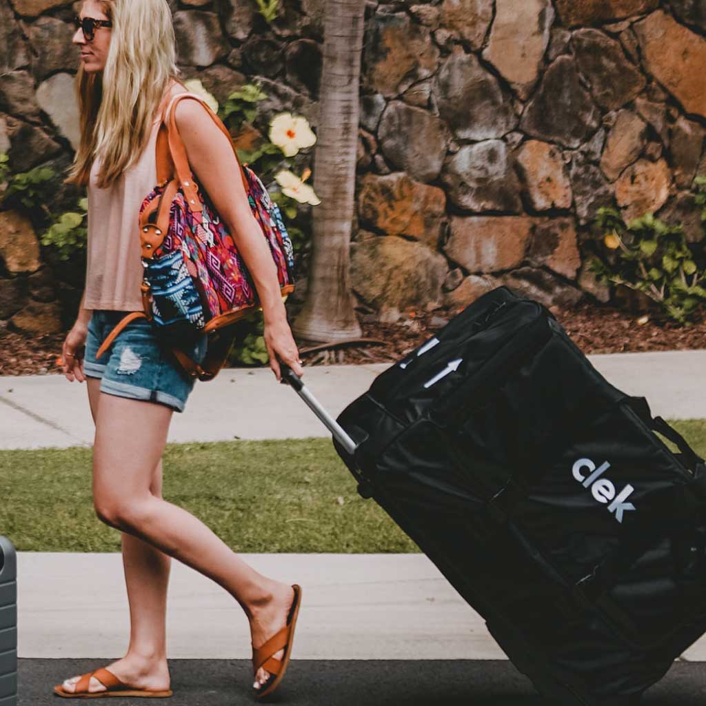Mom walking with a Clek Weelee car seat travel bag