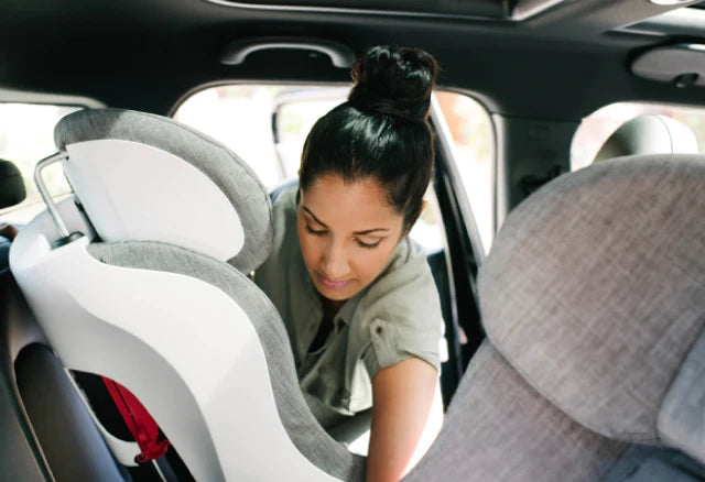 Woman installing her Clek Foonf convertible car seat