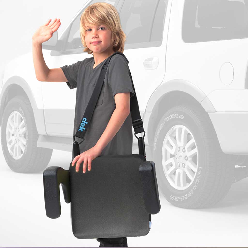 Boy carrying his Clek Ozzi booster seat using the strap-thingy accessory
